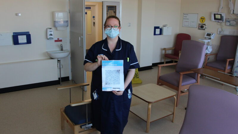 A member of staff holds a barcode poster.