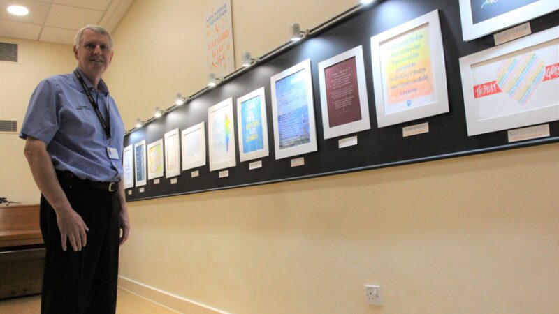 Robert Cooper stands in front of the gallery exhibition.