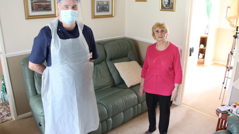 Andy Brown and Brenda Barrett in Brenda's home. Andy wears PPE.