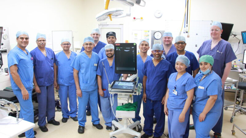 The endoscopy team stand next to the laparoscopic ultrasound machine. They all wear scrubs.