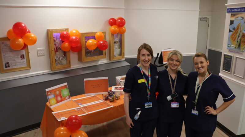 Nursing team in front of sepsis awareness stand.