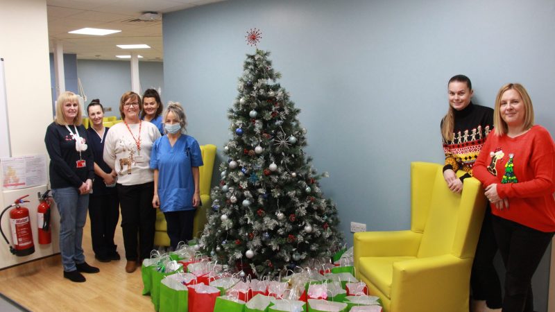 Vicky Lofthouse with her colleagues Emma, Melinda and Claire and some of the chemotherapy unit staff. They stand with a Christmas tree with care packages underneath.