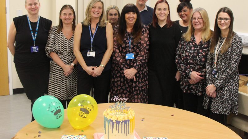 Members of the single point of access team celebrating with balloons and a cake.