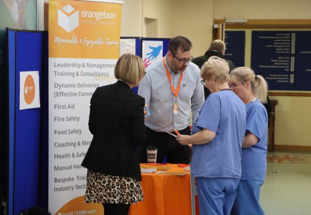 Trust staff at an 'Orangebox training' stand, talking to the stand's hosts.