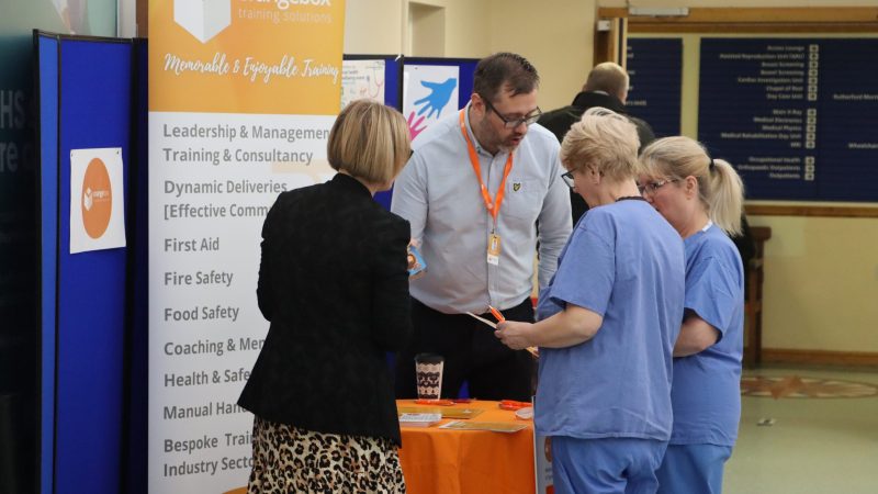 Trust staff at an 'Orangebox training' stand, talking to the stand's hosts.