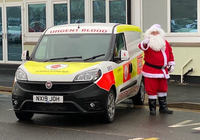 Santa Claus stands next to a Bloodrun van.