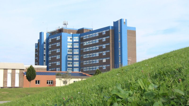 The University Hospital of North Tees over a hill of green grass.