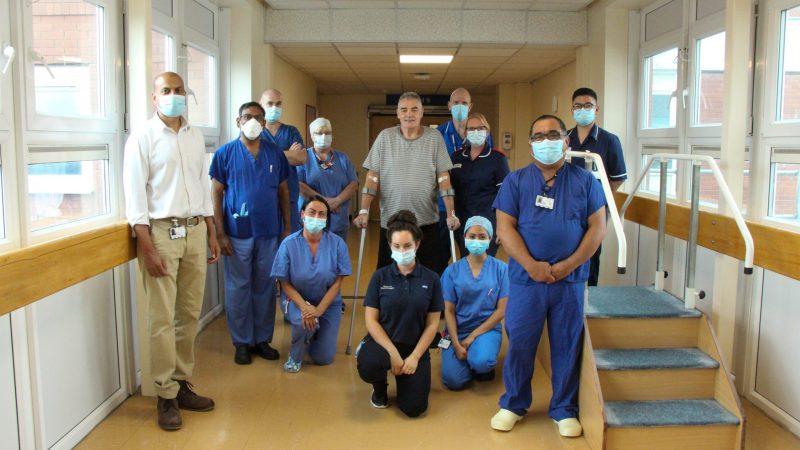 The hip replacement team with Raymond. Raymond stands with crutches.