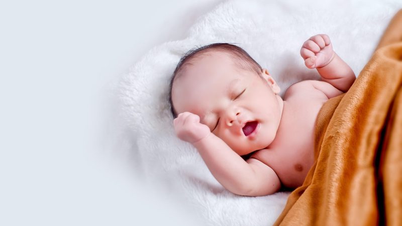 Image of baby covered by orange blanket