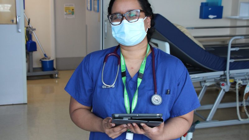 A hospital staff member holds a tablet.