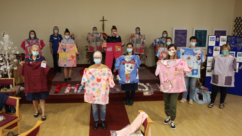 Staff and Maskateers hold up scrubs. Some feature images and patterns, such as Disney Princesses and Paw Patrol.