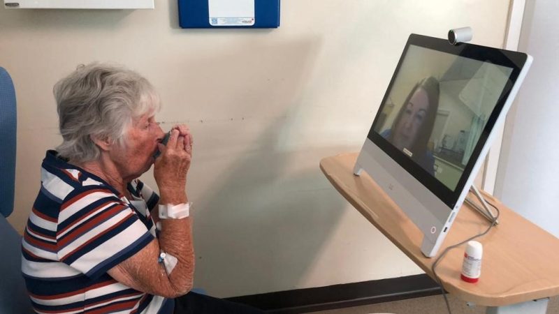A patient talks to a nurse over an iPad screen.